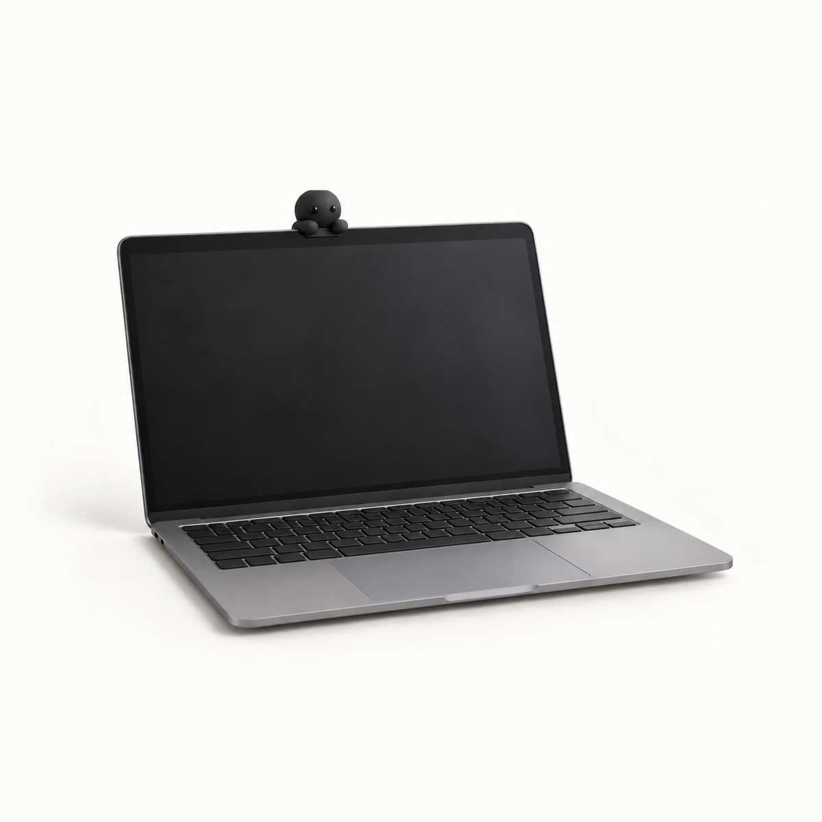 The MacBook Perch in the Black colourway, a slim matte black ledge on a laptop lid, with a Corbie peeking over its edge at the owner.